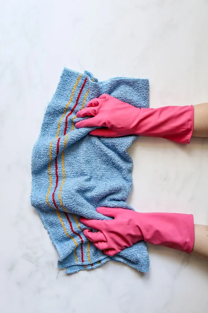 Gloved hand wiping a surface with a blue cloth