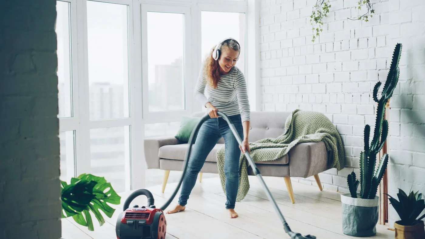 Person vacuuming a living room while wearing headphones