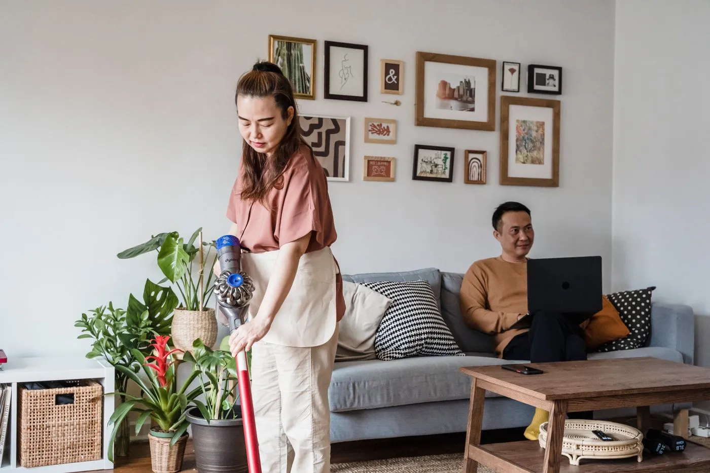 Person vacuuming while another person works at home