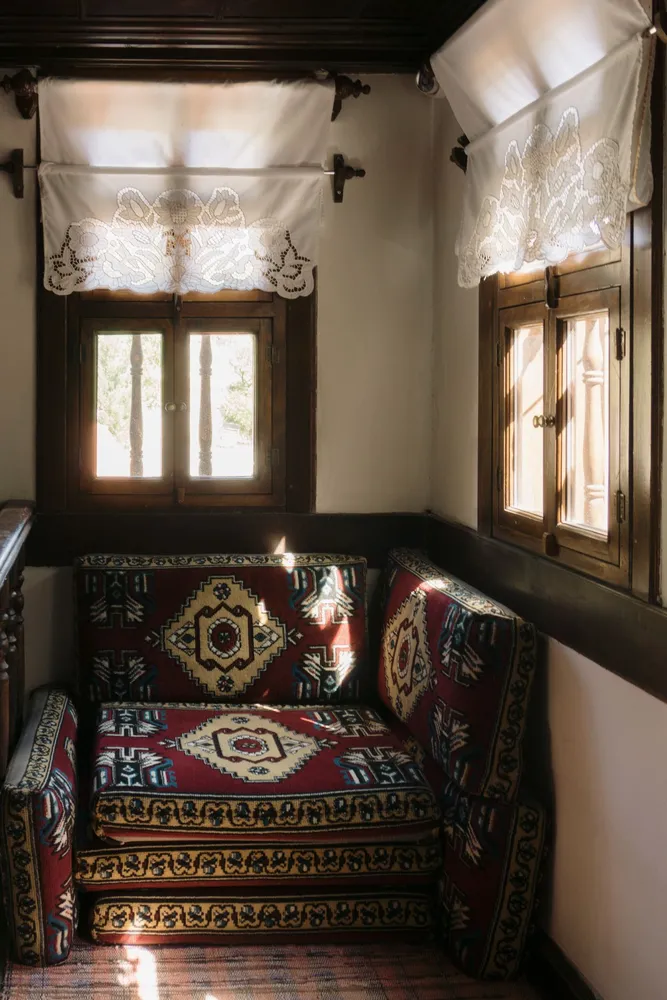 Patterned sofa beside lace curtains