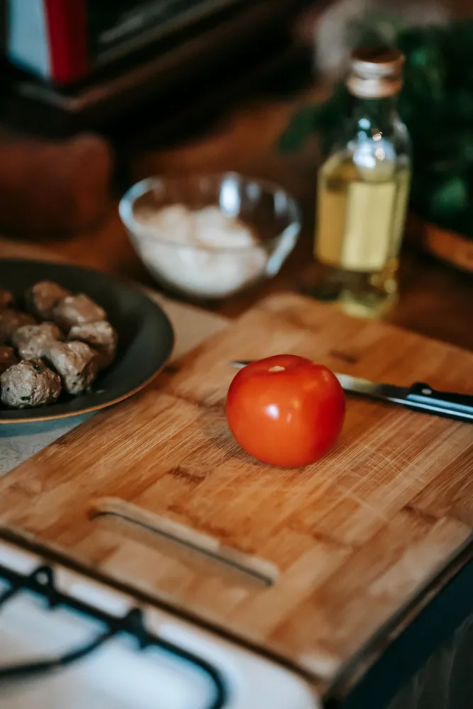 Tomato and kitchen tools on a wooden cutting board