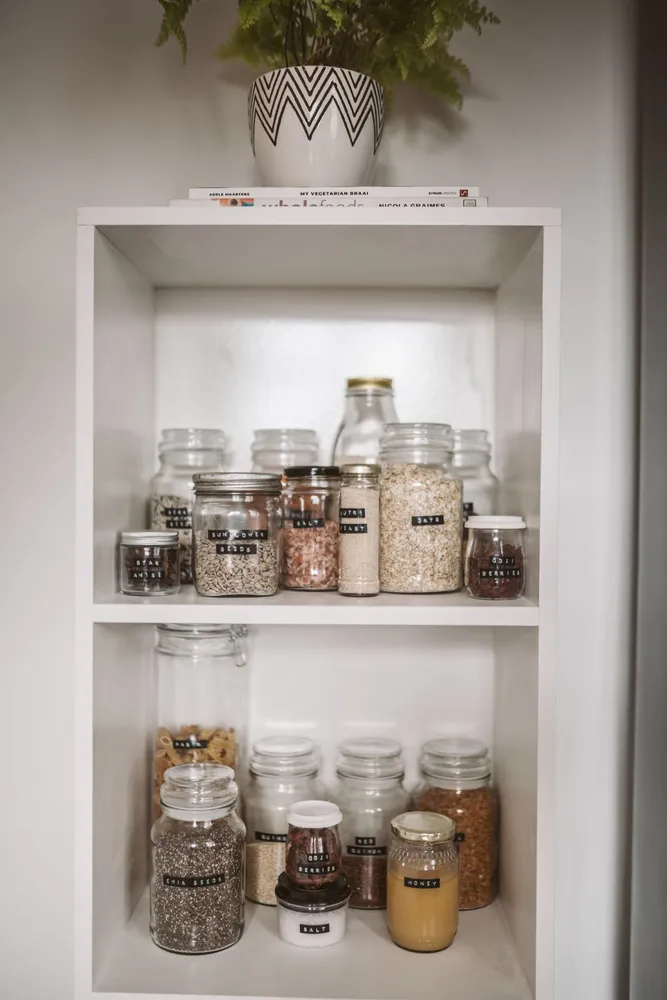 Labeled jars on white pantry shelves